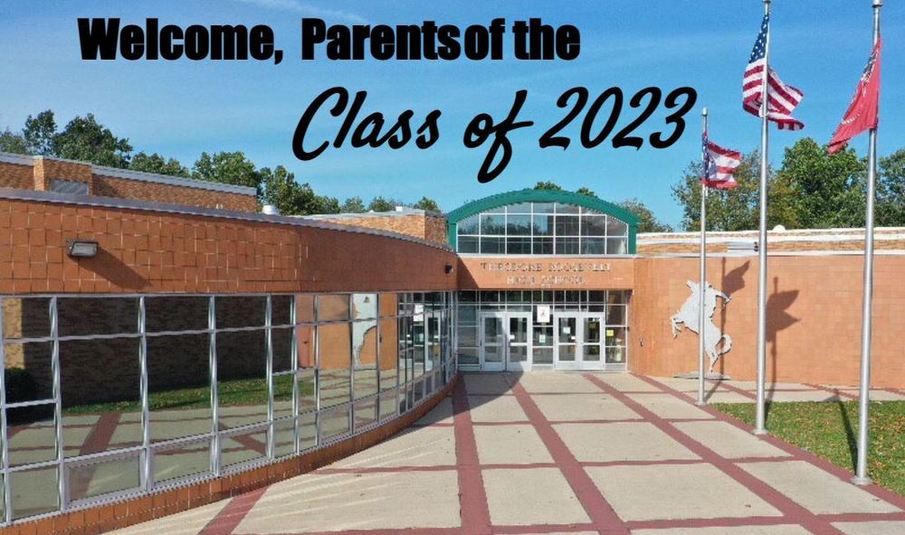 Welcome Parents of the Class of 2023 event entrance to Theodore Roosevelt High School brick building with Silver rough riders lots of windows and three flag poles